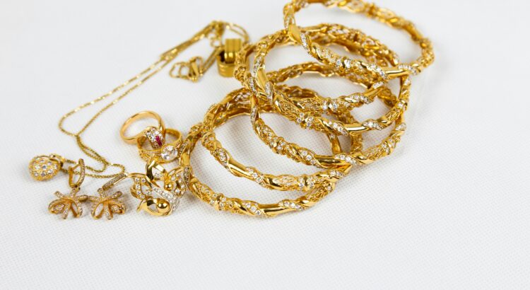 An assortment of gold necklaces, rings, earrings and bangles in a pile on a white background