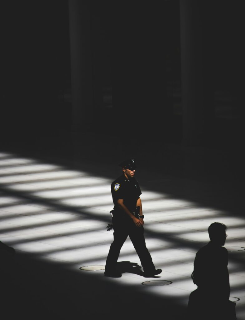 NYC Police officer walking in the shade of a building